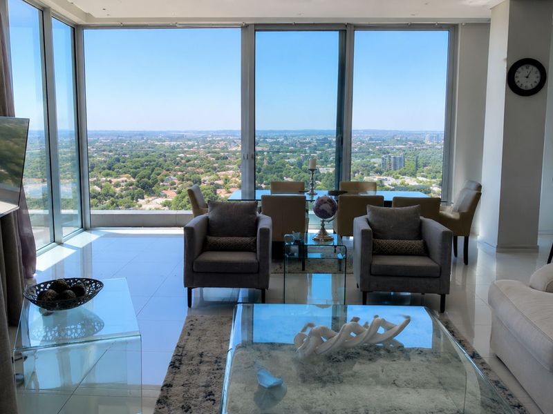 Spacious open-plan living and dining area featuring floor-to-ceiling windows with expansive panoramic views and high-quality tiled flooring.