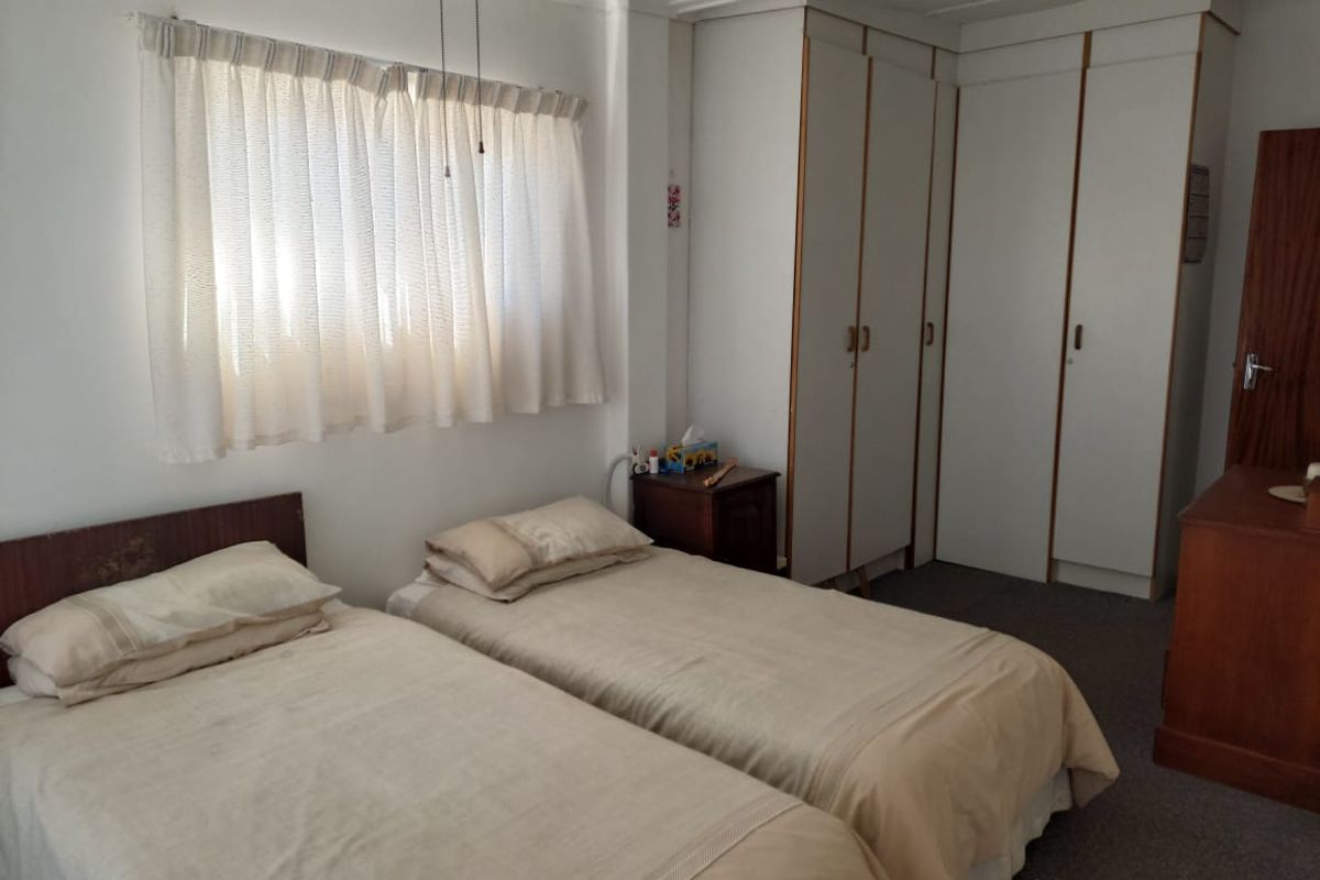 A functional bedroom featuring built-in cupboards and a ceiling fan, offering a neutral canvas for potential updates.