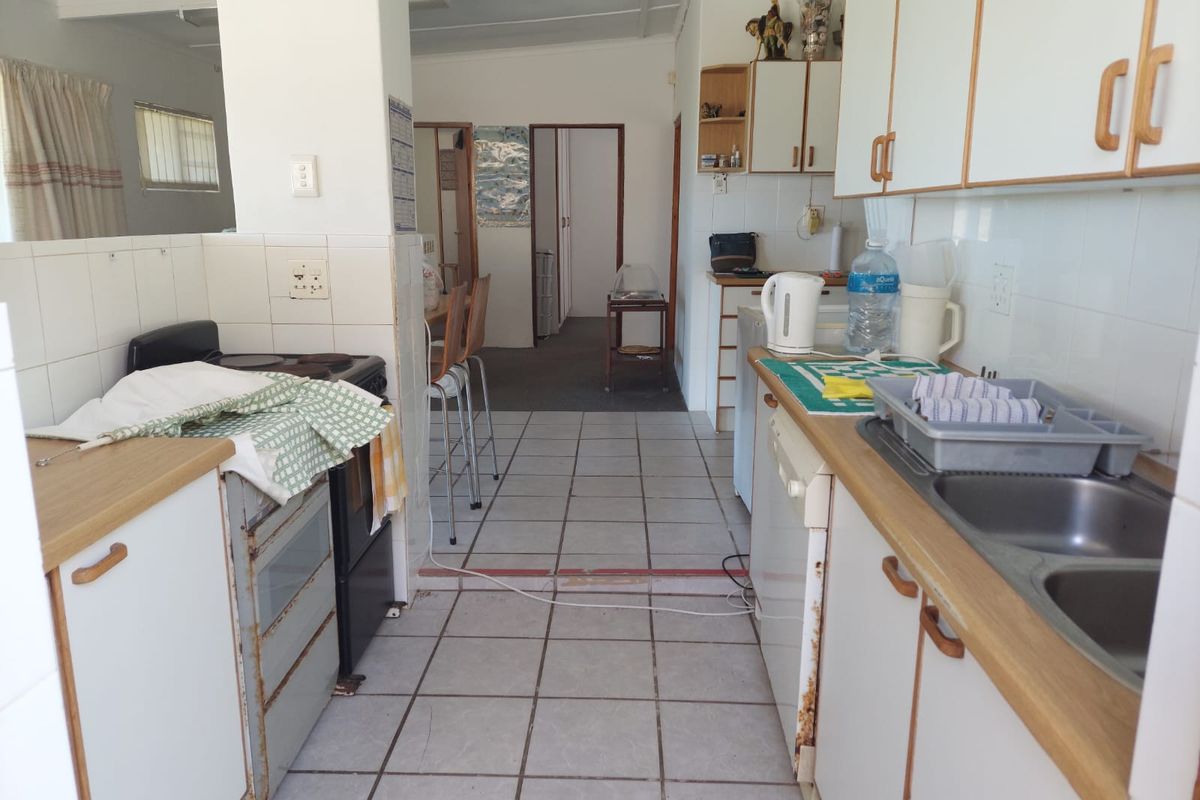 A dated kitchen featuring laminate countertops, tiled splashbacks, and built-in cabinetry, showing signs of wear and requiring modernization.