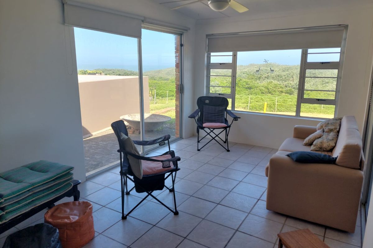 Bright living area featuring large windows and sliding glass doors with scenic views, tiled flooring, and a ceiling fan.