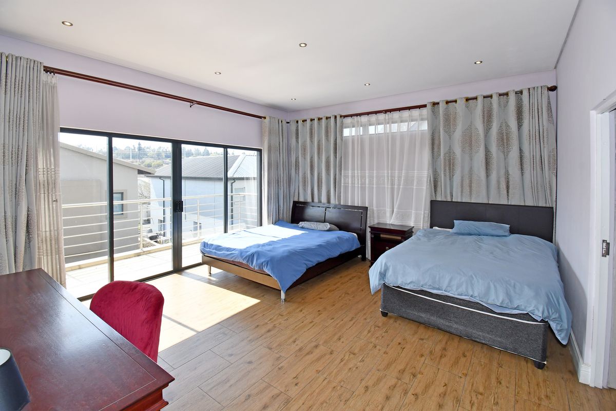 Spacious bedroom featuring wood-look tile flooring, recessed downlights, and large sliding glass doors providing direct access to an outdoor balcony.