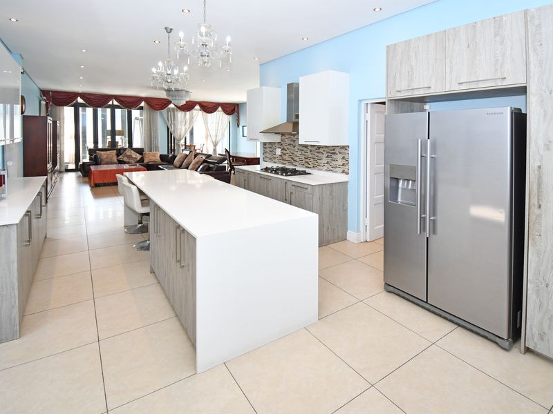 Spacious open-plan kitchen featuring a large central island, modern cabinetry, quartz countertops, and integrated appliances, flowing seamlessly into the living area.