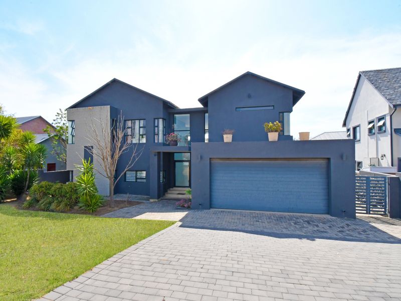 Modern double-story residential home featuring a dark exterior finish, paved driveway, and integrated double garage.