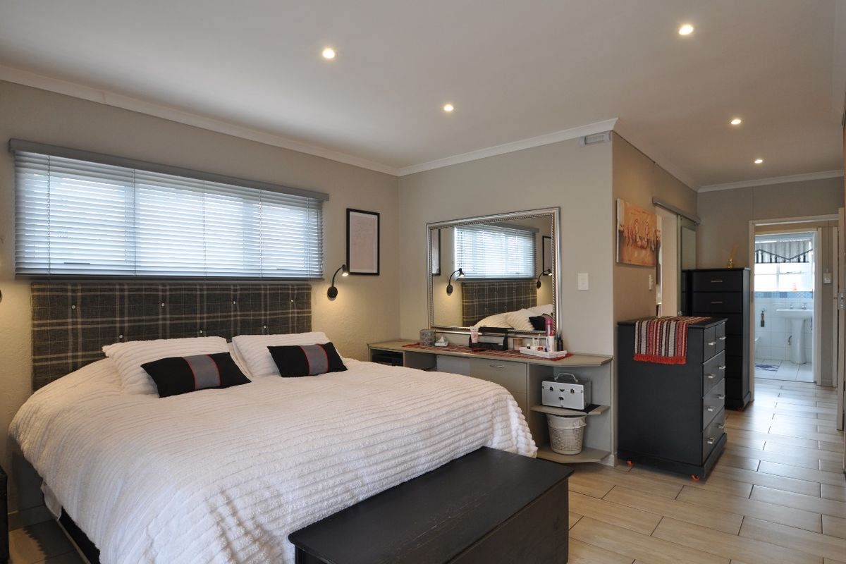 Spacious bedroom featuring tiled flooring, recessed downlighting, and a built-in vanity unit, with an adjoining view into the bathroom area.