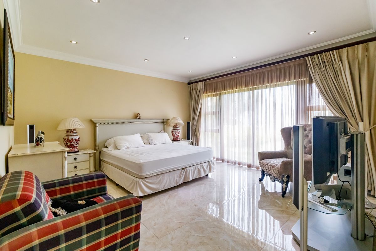 Spacious bedroom featuring polished marble flooring, recessed downlighting, and large sliding glass doors that provide ample natural light.