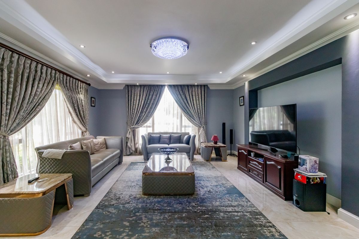Spacious living room featuring elegant cove lighting, recessed ceiling lights, polished tiled flooring, and a dedicated media wall niche.