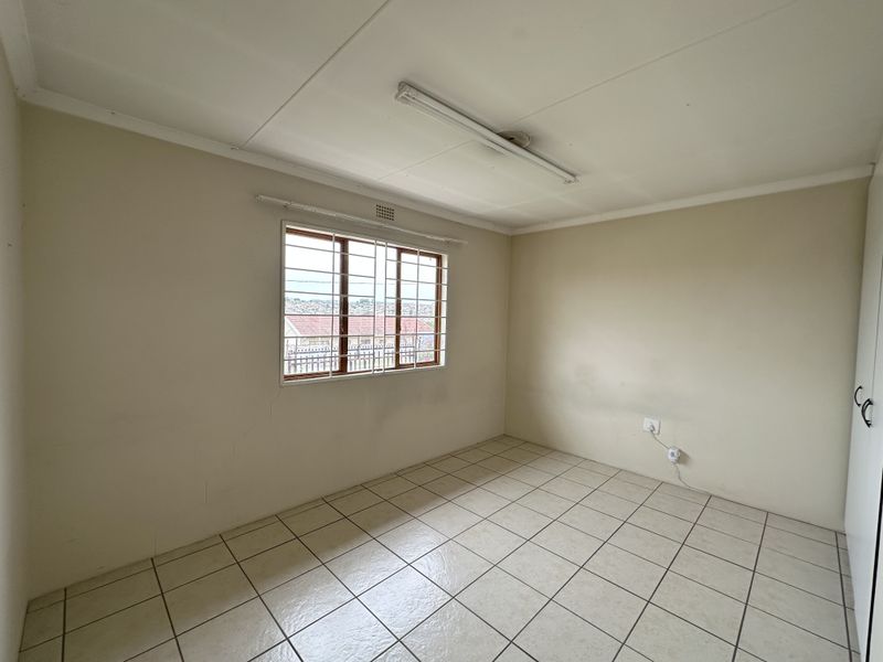 An empty bedroom featuring tiled flooring, built-in cupboards, and security bars on the window, offering a blank canvas for potential updates.