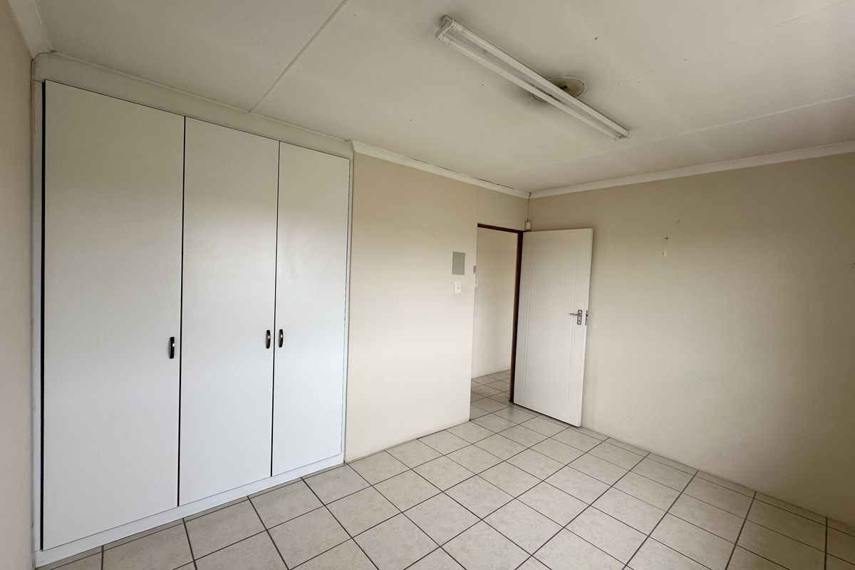 An empty bedroom featuring tiled flooring, built-in cupboards, and a neutral color palette, offering a blank canvas for personalization.
