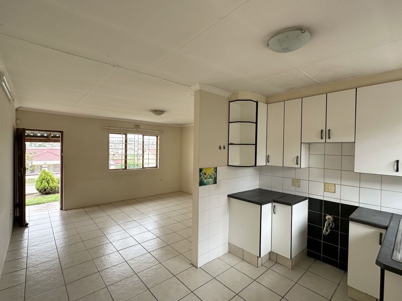 Open plan living and kitchen area featuring tiled flooring, built-in cabinetry, and direct access to the exterior, offering a blank canvas for renovation.