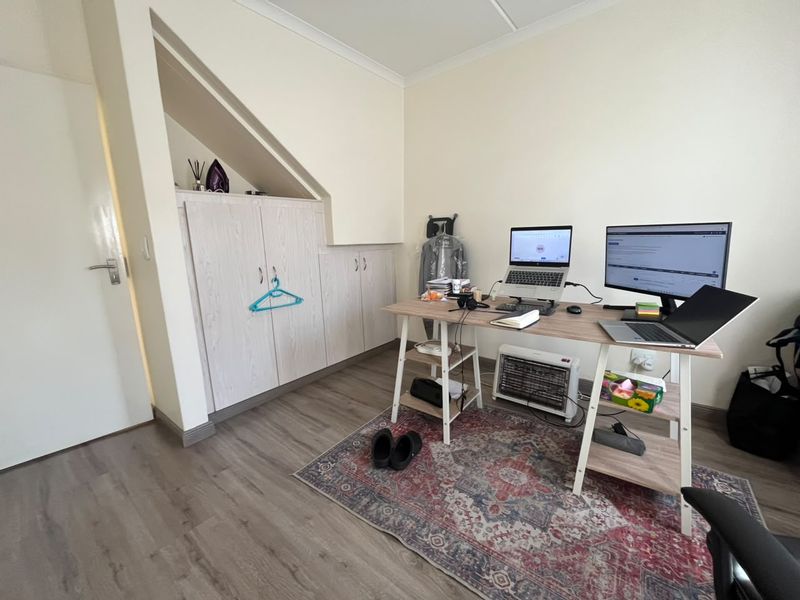 A functional home office space featuring built-in under-stair cabinetry and durable laminate flooring, providing a practical workspace within the apartment.