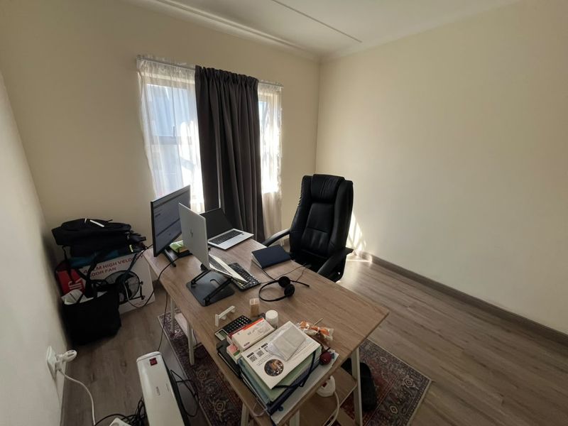 A functional home office space featuring light-toned laminate flooring and neutral wall finishes, providing a versatile area for remote work or study.