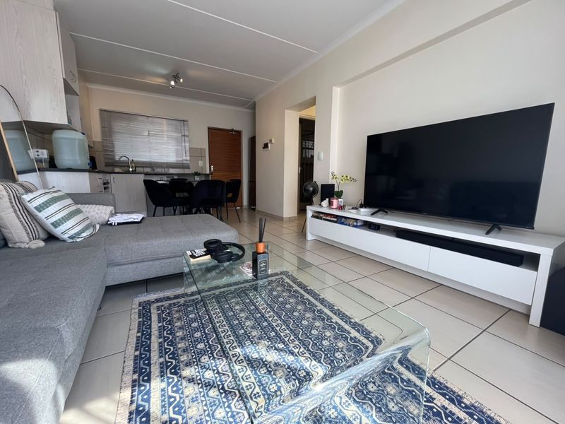 An open-plan living and kitchen area featuring tiled flooring, modern cabinetry, and a functional layout suitable for comfortable apartment living.