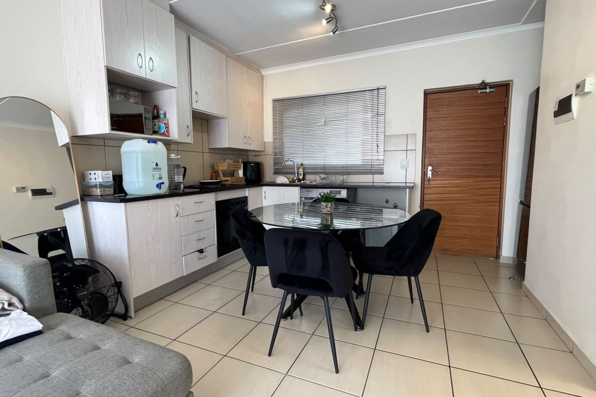 Open-plan kitchen area featuring light-toned built-in cabinetry, tiled flooring, and a functional layout with integrated oven and sink.