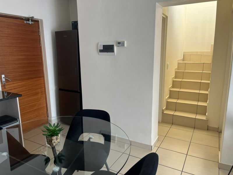 Entrance area featuring tiled flooring, a timber door, and a staircase leading to the upper level.