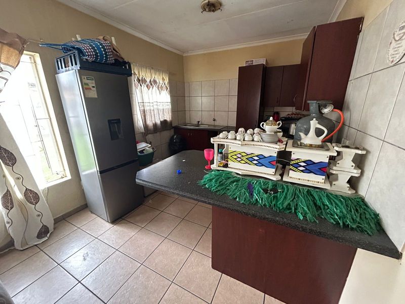 A functional kitchen featuring dark built-in cabinetry, tiled flooring, a tiled backsplash, and a breakfast bar area with laminate countertops.