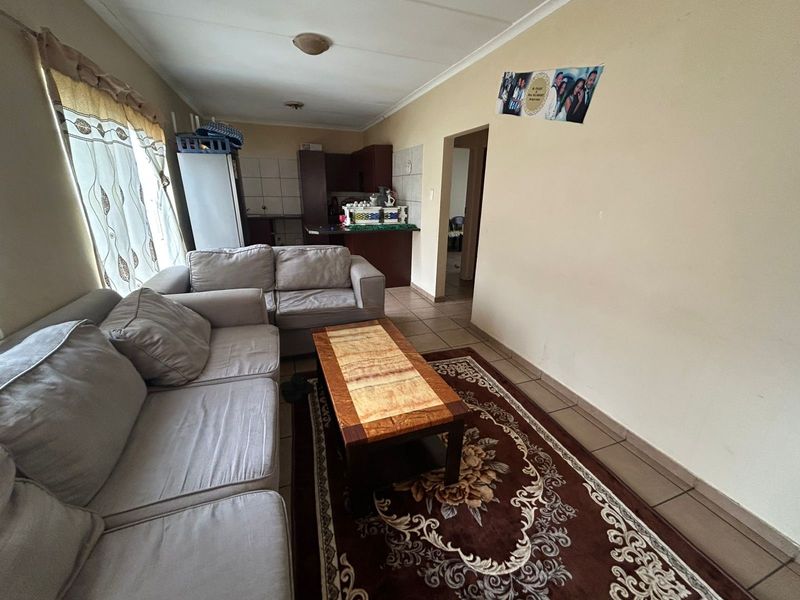 Open plan living area featuring tiled flooring and a connected kitchen space with built-in cabinetry and countertops.