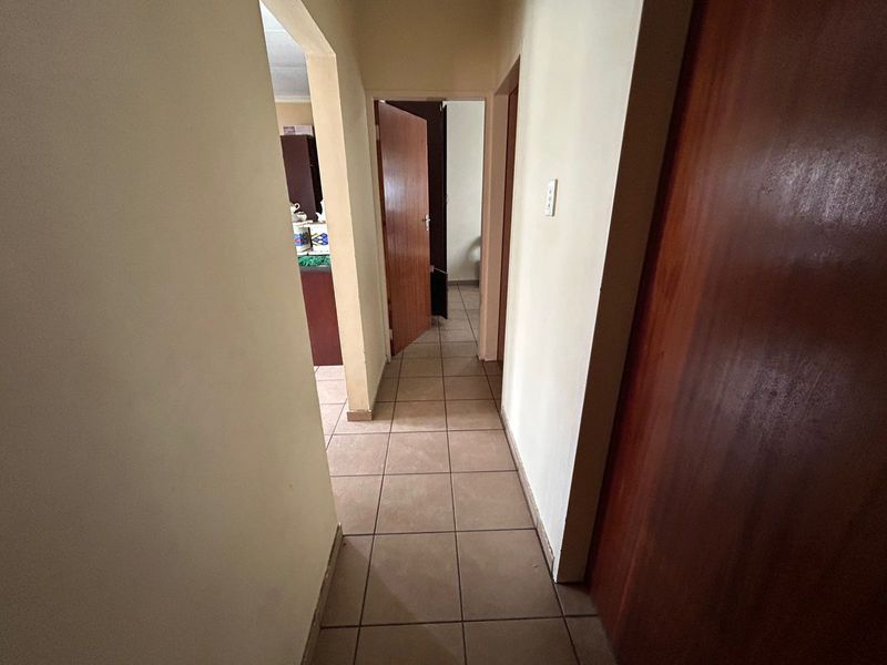 A functional hallway featuring tiled flooring and wooden doors, providing access to various rooms within the townhouse.