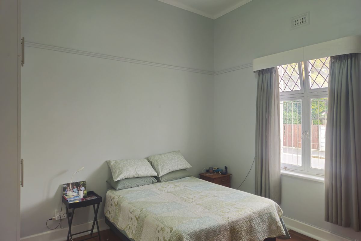 A well-maintained bedroom featuring classic leaded glass windows, original picture rails, and warm timber flooring, offering a bright and comfortable living space.