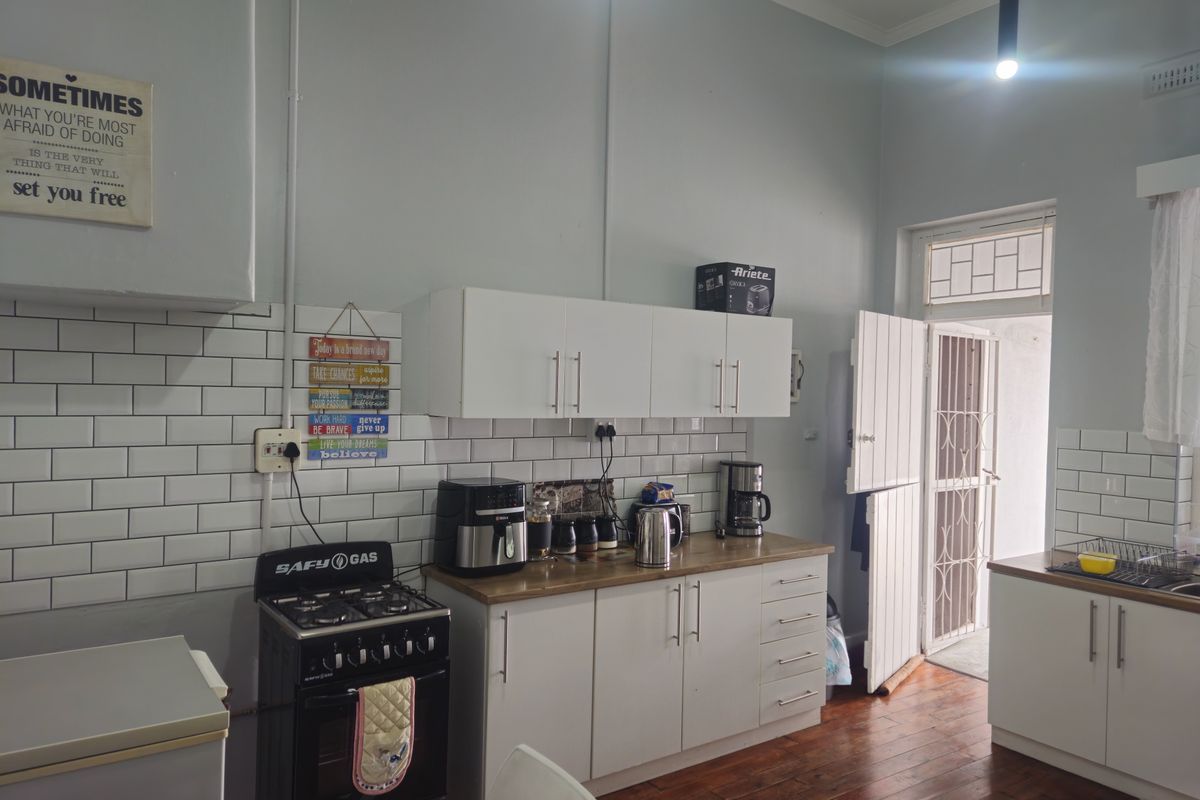 A functional kitchen featuring white cabinetry, subway tile backsplash, wooden countertops, and a gas stove, with direct access to an outdoor area.