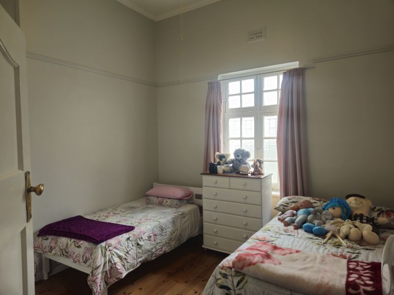 A bedroom featuring original timber flooring, a classic multi-pane window, and traditional picture rails, offering a neutral canvas for updates.
