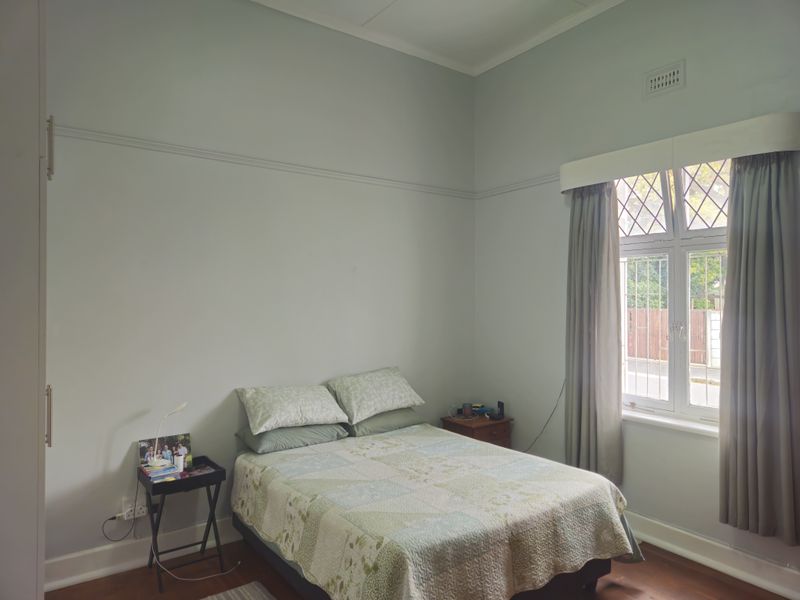 A well-maintained bedroom featuring classic leaded glass windows, original picture rails, and warm timber flooring, offering a bright and comfortable living space.