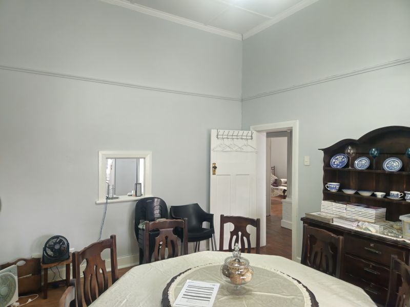 Dining room featuring high ceilings with decorative cornicing, picture rails, and a serving hatch connecting to the kitchen area.