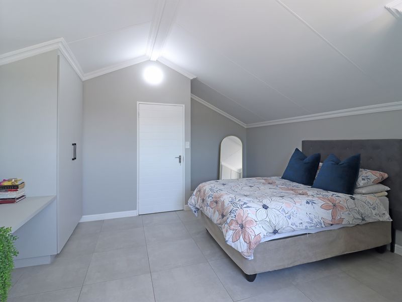 A well-maintained bedroom featuring vaulted ceilings, crown molding, tiled flooring, and built-in cupboards, offering a clean and modern aesthetic.