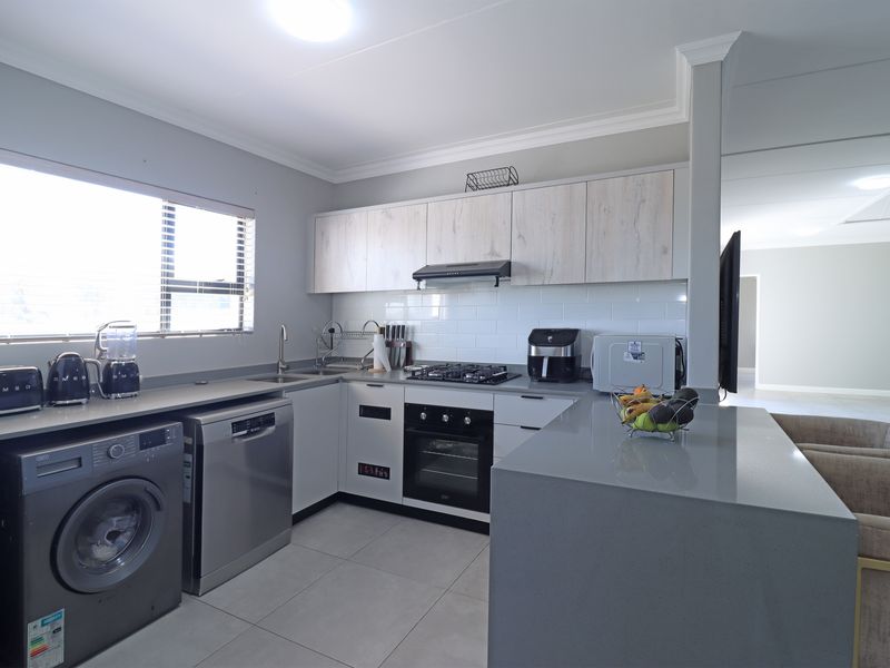 Modern kitchen featuring stone countertops, subway tile backsplash, built-in gas hob and oven, and a functional breakfast bar area.