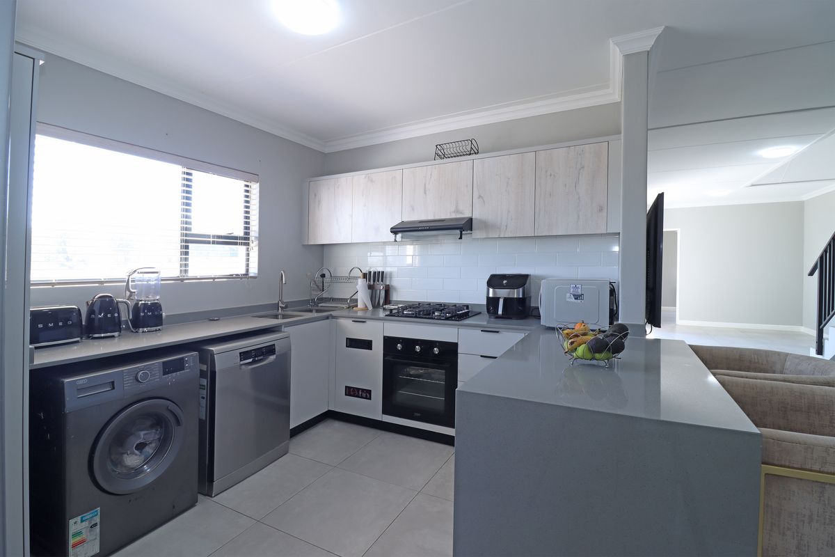 Modern kitchen featuring stone countertops, subway tile backsplash, built-in gas hob and oven, and a functional breakfast bar area.