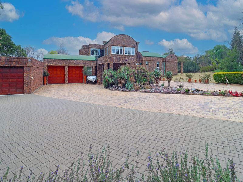 A spacious face brick family home featuring a large paved driveway, triple garage, and established front garden.