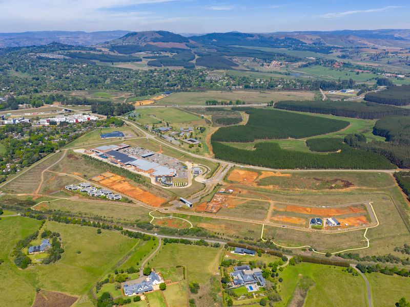 An expansive aerial view showing the surrounding landscape, including residential plots, commercial infrastructure, and green spaces within the estate.
