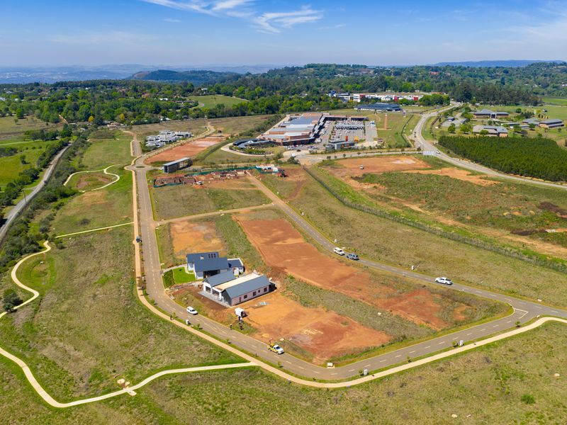 Aerial view of a residential estate development featuring paved road infrastructure and surrounding green landscape.