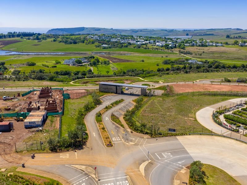 Aerial view of a residential estate entrance featuring a gated security access point, paved road network, and surrounding landscaped grounds.