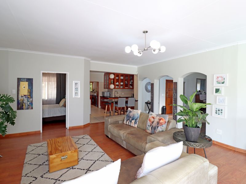Spacious open-plan living area featuring laminate flooring, arched architectural transitions, and a view into the adjacent kitchen and bedroom.