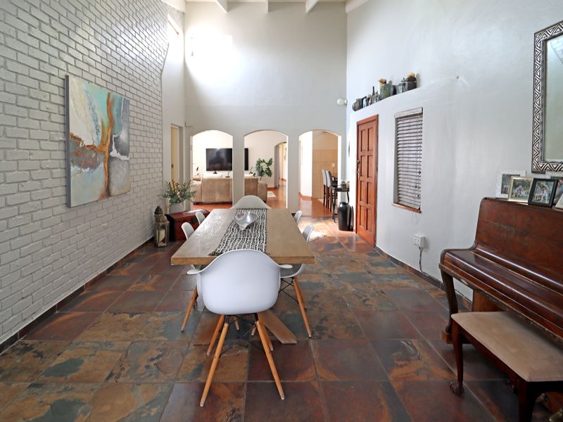 Spacious dining area featuring high vaulted ceilings, exposed brick feature wall, and durable slate tile flooring with arched access to adjacent living spaces.