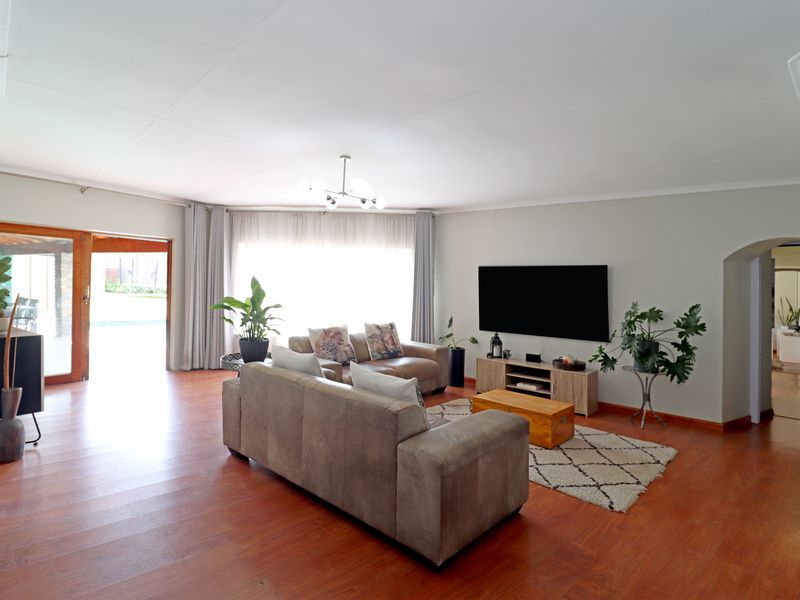 Spacious living room featuring warm laminate flooring, a modern light fixture, and a sliding glass door providing access to the outdoor area.