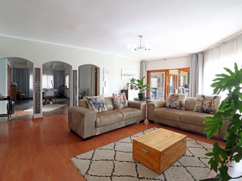 Spacious living room featuring warm laminate flooring, elegant arched doorways leading to adjacent areas, and large sliding glass doors providing natural light.