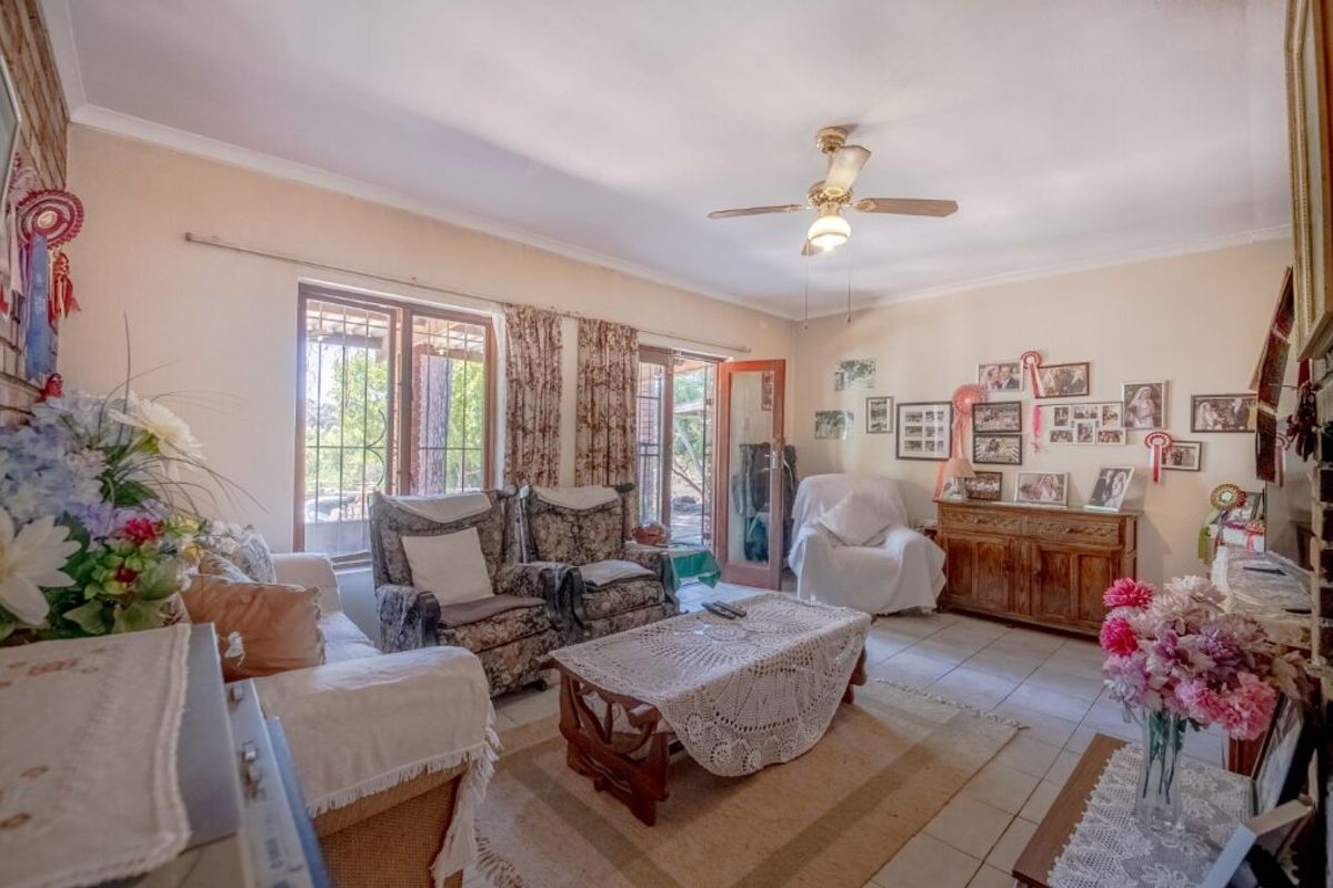 A living room featuring tiled flooring, a ceiling fan, and sliding glass doors providing access to the outdoor area.