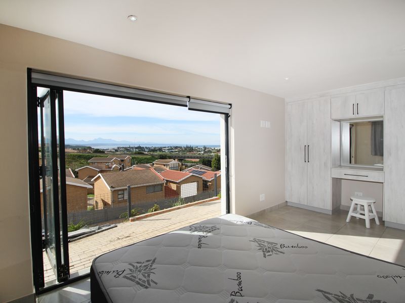 Spacious bedroom featuring built-in cupboards, a vanity area, tiled flooring, and large bi-fold doors opening to a scenic outdoor view.