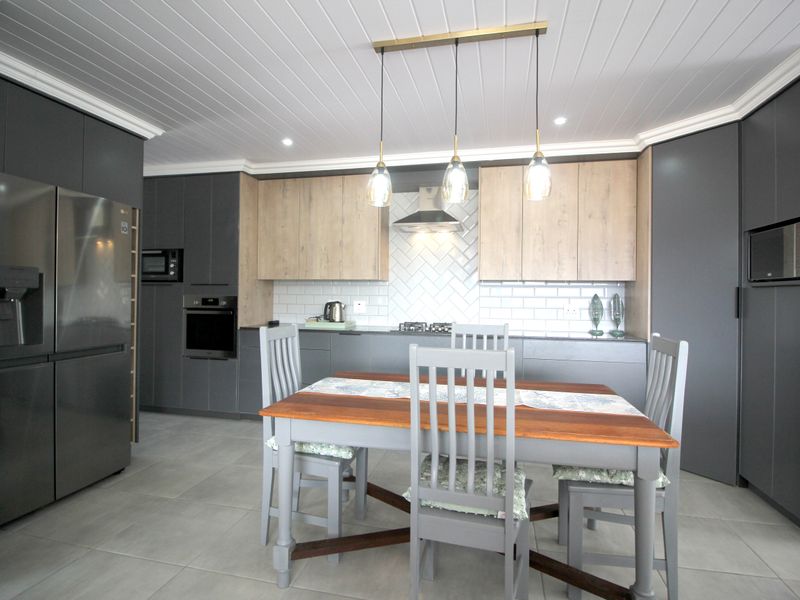 Modern kitchen featuring two-tone cabinetry, subway tile backsplash, built-in appliances, and a tongue and groove ceiling with contemporary pendant lighting.