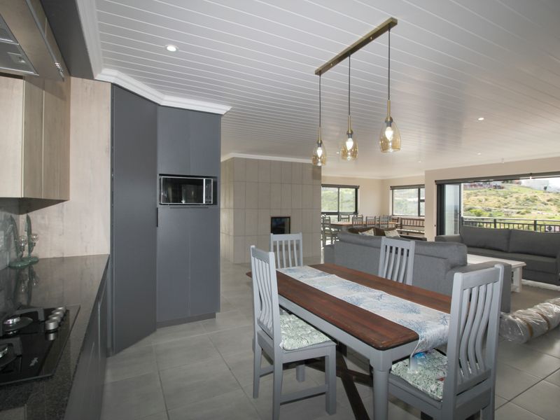 Modern open-plan kitchen and living area featuring contemporary cabinetry, a gas hob, fireplace, and seamless flow to an outdoor balcony with scenic views.