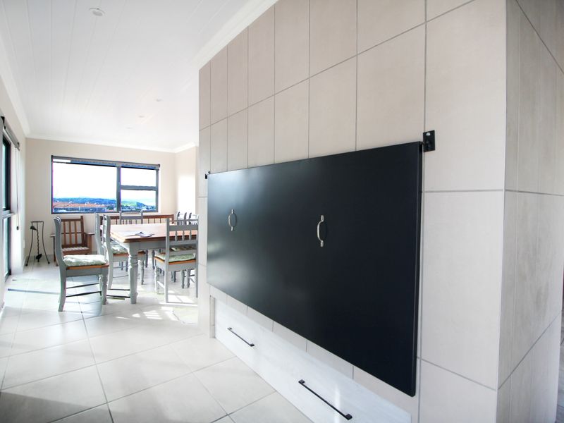 Open plan living area featuring large format wall tiles, built-in cabinetry, and neutral floor tiles with natural light and views.