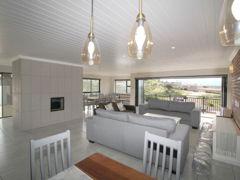 Spacious open-plan living and dining area featuring tiled floors, a modern built-in fireplace, exposed brick accents, and large sliding doors opening to a balcony.
