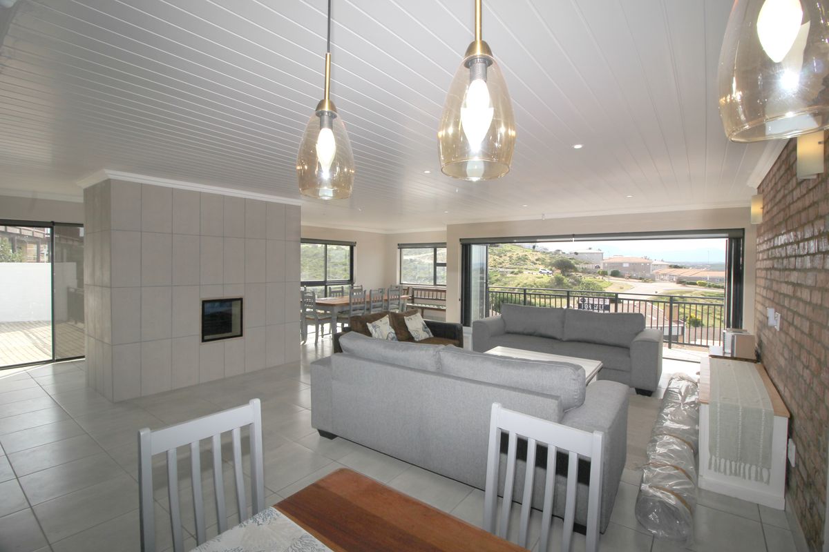 Spacious open-plan living and dining area featuring tiled floors, a modern built-in fireplace, exposed brick accents, and large sliding doors opening to a balcony.