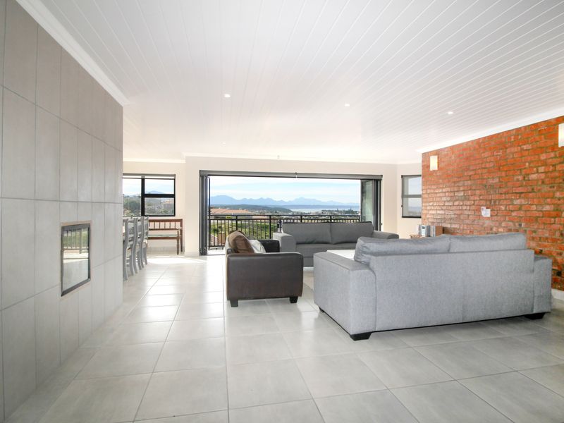 Spacious open-plan living area featuring an exposed brick wall, tiled fireplace, and large stacking doors opening to a scenic balcony view.