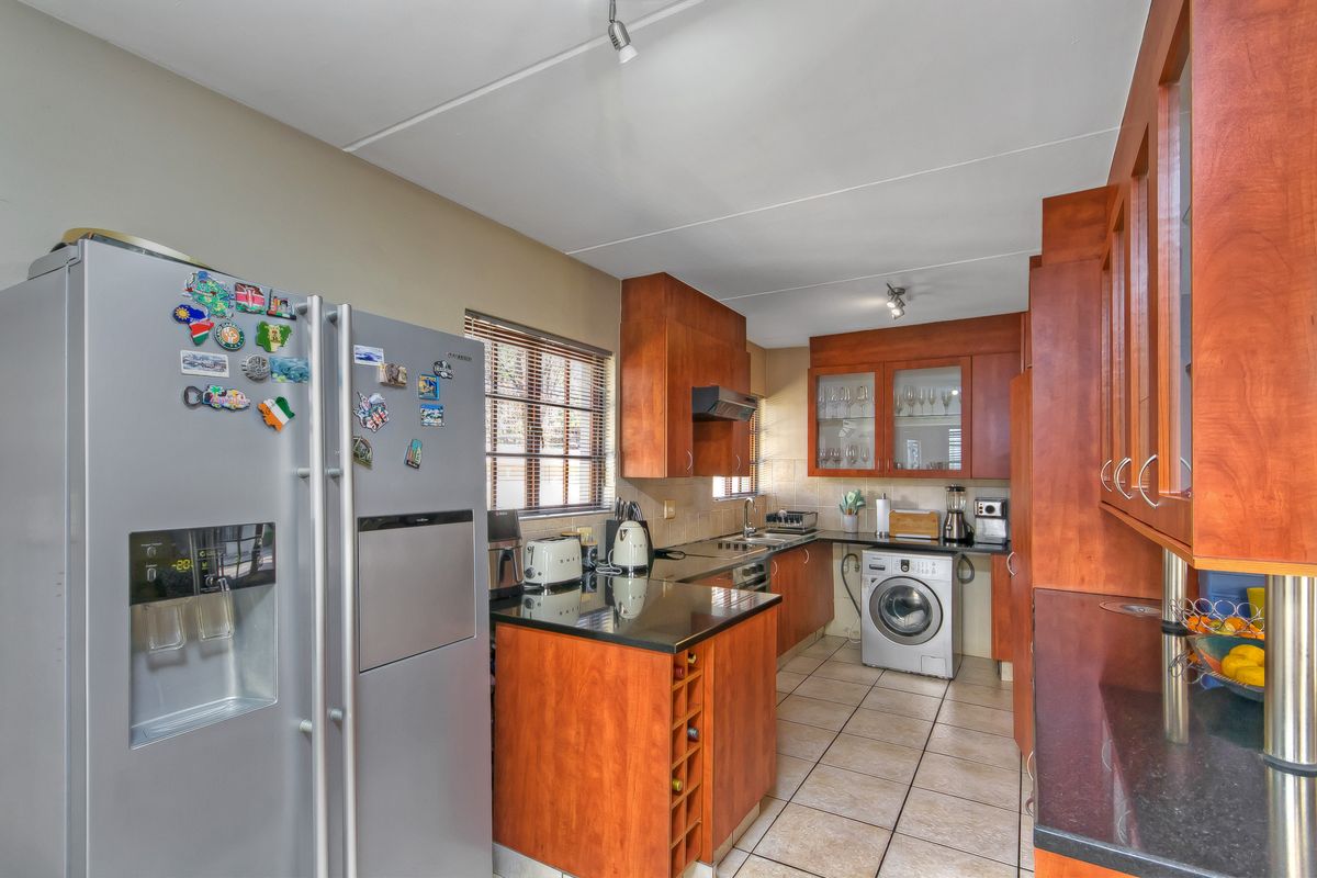 A functional kitchen featuring warm-toned wooden cabinetry, granite countertops, tiled flooring, and integrated laundry facilities, offering a practical layout for daily use.