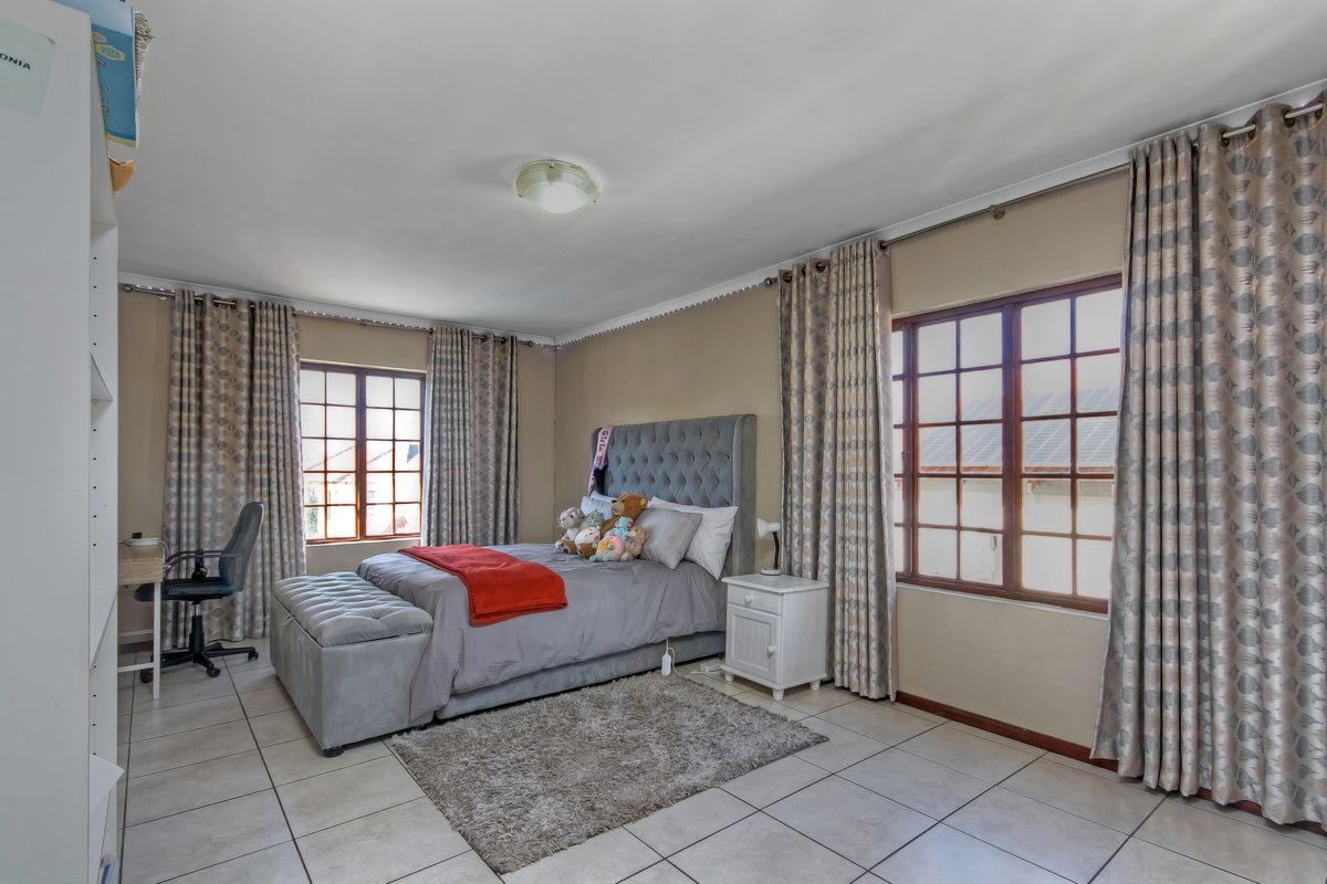 A spacious bedroom featuring tiled flooring, large wooden-framed windows, and coved ceiling detailing, providing a functional and well-lit living space.
