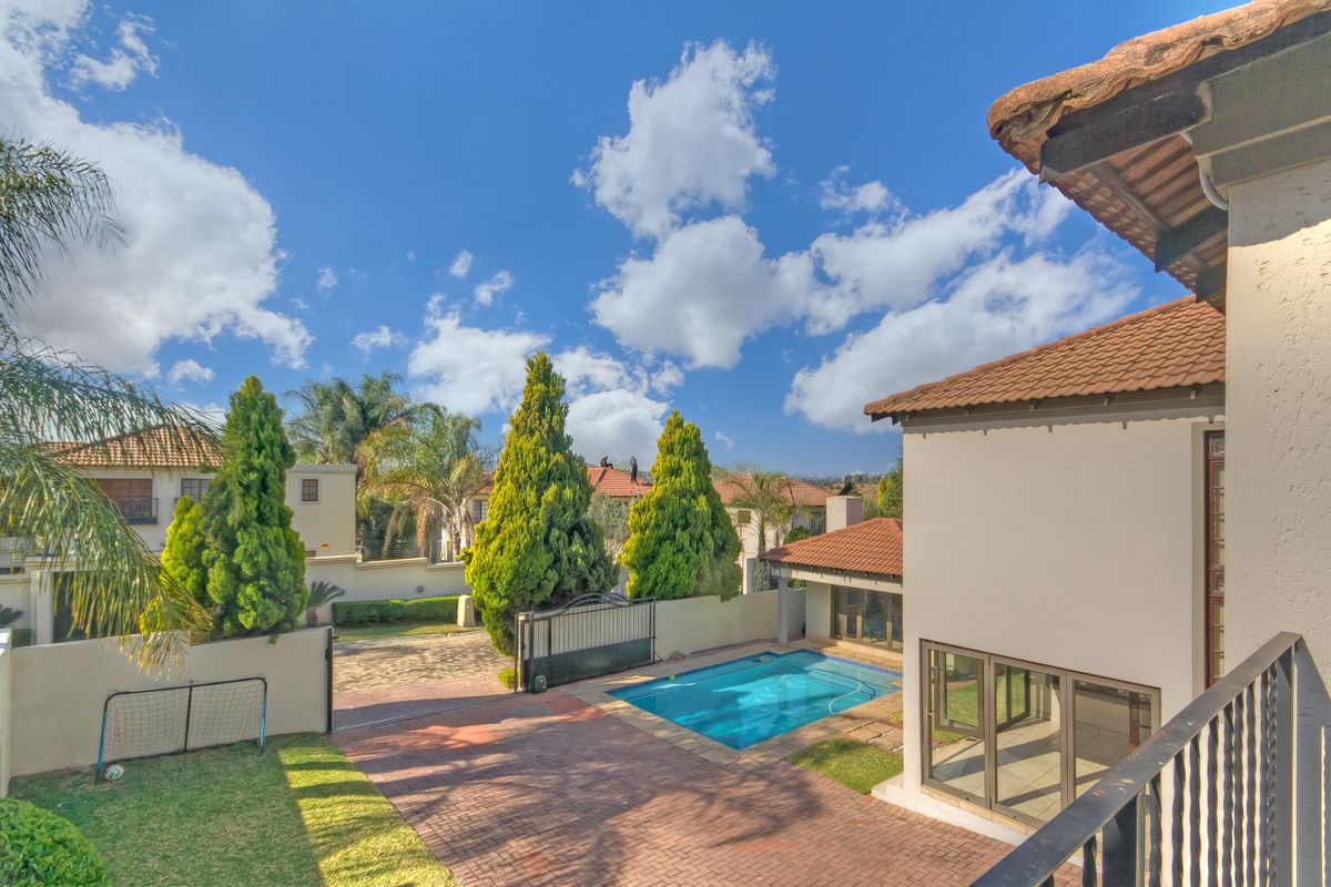 Elevated view of a rear garden featuring a swimming pool, paved courtyard, and access to the main house via sliding doors.