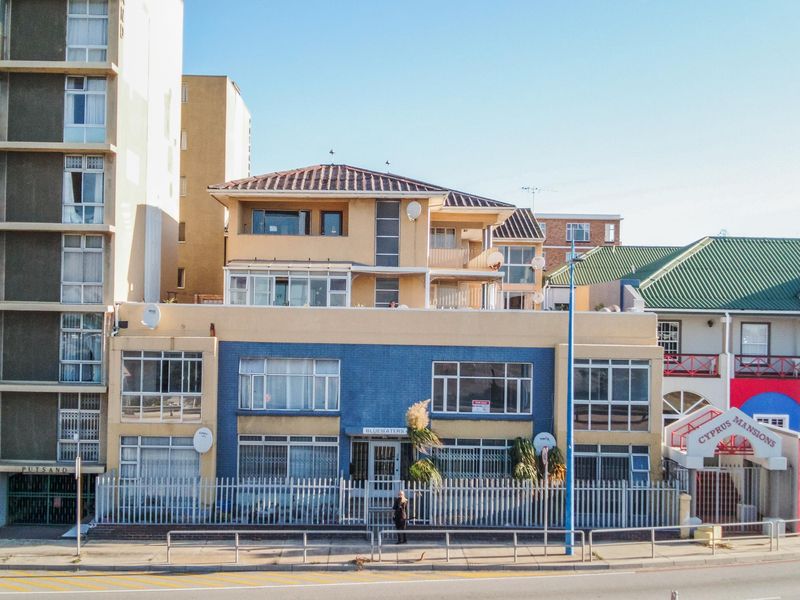 Front elevation of the Bluewaters apartment building, featuring a multi-story facade with security fencing and aluminium window frames.