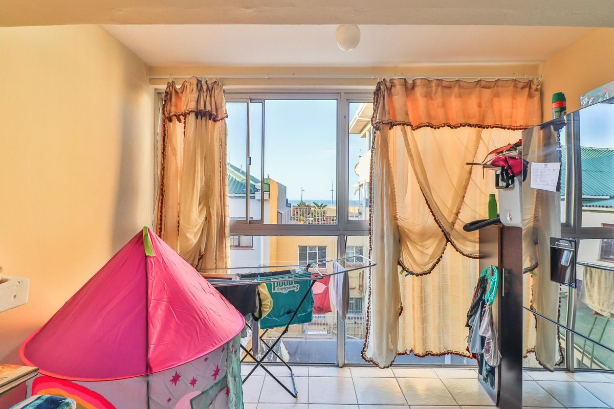 A bedroom featuring tiled flooring and a large sliding window that provides natural light and an urban view.